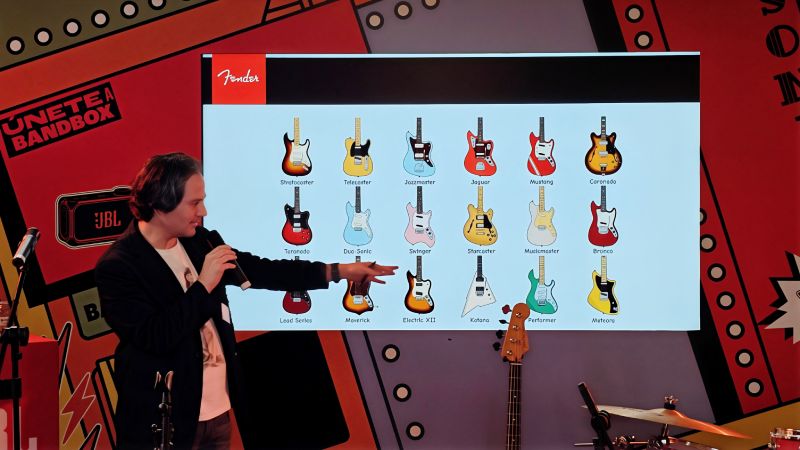 Presentador frente a una pantalla que muestra ilustraciones de modelos de guitarra Fender durante una sesión informativa.