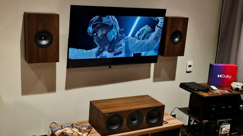 Sistema de entretenimiento en casa con pantalla, bocinas y equipo de audio en un entorno doméstico.