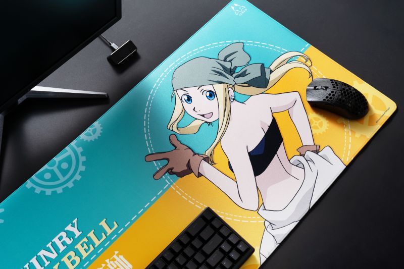 Escritorio con alfombrilla temática de anime, teclado y mouse sobre una superficie ilustrada con un personaje rubio y elementos mecánicos.