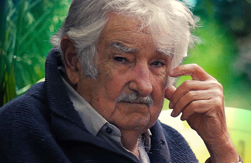 Retrato de un hombre mayor sentado al aire libre, con expresión serena y vegetación de fondo, acompañado del título del documental.
