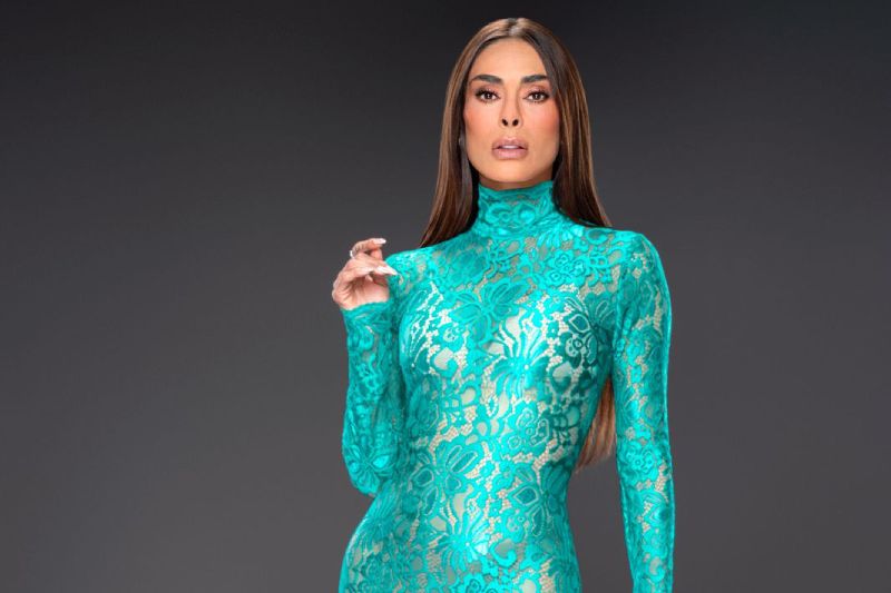 Retrato promocional de integrante del equipo de “La Casa de los Famosos México” Fotografía de una persona posando en estudio con un vestido largo turquesa de encaje, en fondo neutro.
