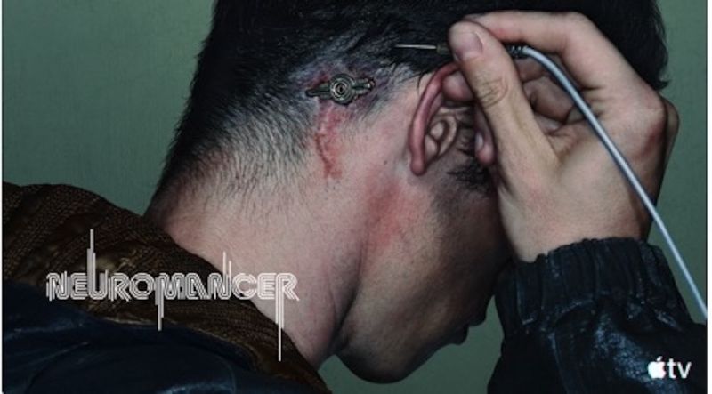 Fotografía de plano corto en perfil de la nuca y cabeza de un hombre con cabello oscuro corto. Detrás de su oreja se aprecia un implante cibernético metálico circular insertado en la piel con marcas de cicatriz y una pequeña incisión ensangrentada, mientras la mano sostiene una clavija conectada al puerto. En la esquina inferior izquierda aparece el logotipo oficial de "Neuromancer" y en la inferior derecha el isotipo de Apple TV.
