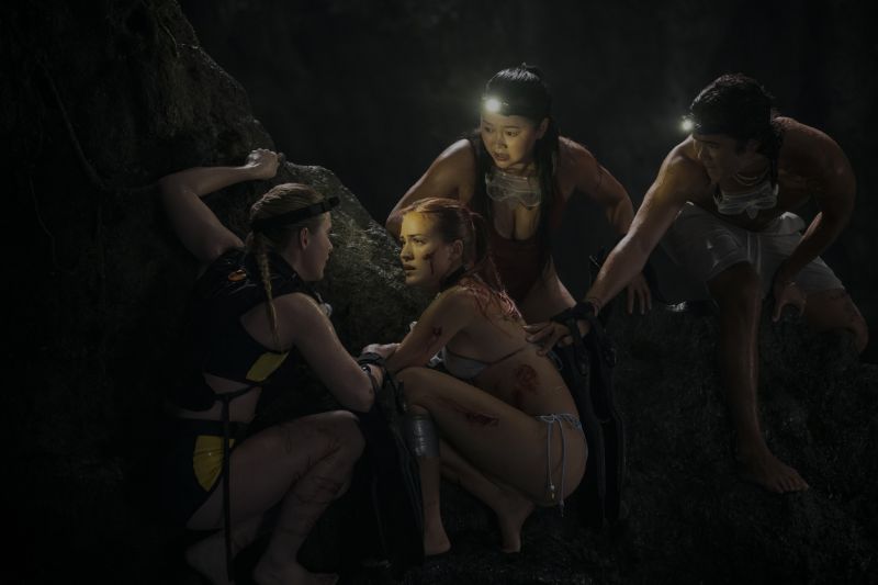 Grupo de jóvenes dentro de una cueva oscura, iluminados por lámparas frontales mientras auxilian a un integrante herido.
