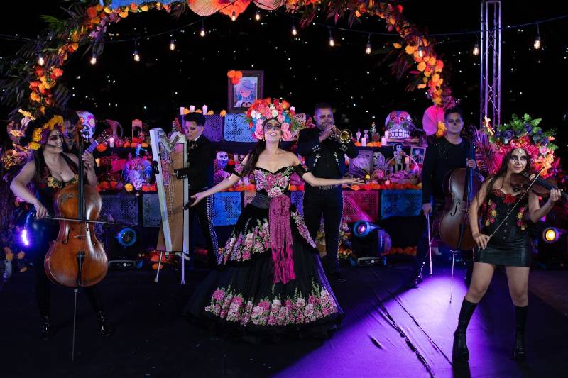 Mujeres caracterizadas por Día de Muertos tocando instrumentos y cantando