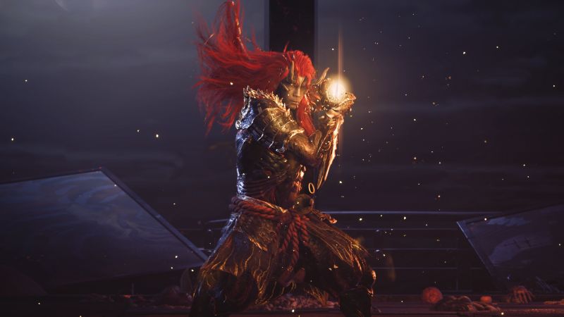 Captura de pantalla en plano medio frontal de Miyamoto Musashi en su forma Oni completamente despierta durante una batalla nocturna. El personaje luce una melena larga y esponjada de color rojo encendido que flota hacia arriba, un rostro demoníaco con cuernos dorados sobre la frente y una armadura samurai oscura con relieves dorados y cuerdas rojas trenzadas en la cintura. Sostiene su espada con ambas manos cerca del pecho, generando un resplandor dorado y brillante que emite destellos y chispas de luz alrededor, con ruinas de edificios inclinados al fondo bajo un cielo nocturno oscuro.
