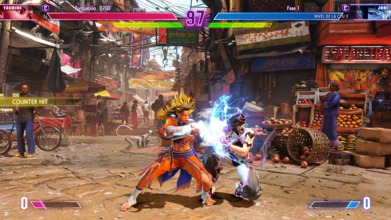 Yasmine enfrentando a Juri en Street Fighter 6 Captura de pantalla de combate entre Yasmine con el Color 5 de su Atuendo 1 (traje naranja y cabello rubio erizado) ejecutando un ataque directo contra Juri en un escenario de mercado al aire libre.