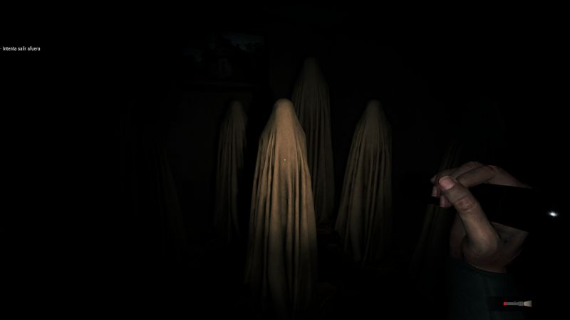 Sala oscura con varias figuras humanas cubiertas por telas, iluminadas parcialmente por una linterna.