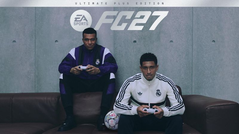 Imagen de portada oficial de EA SPORTS FC 27 Ultimate Plus Edition. En la parte superior sobre un fondo de pared de concreto gris aparece el logotipo de EA SPORTS FC 27 en letras blancas. En el centro, Kylian Mbappé y Jude Bellingham, futbolistas del Real Madrid, posan sentados en un sofá de piel marrón oscuro. Mbappé vista un conjunto deportivo de entrenamiento del Real Madrid color morado con negro y sostiene un control de consola blanco en las manos. A su lado, Jude Bellingham porta una chaqueta deportiva Adidas del Real Madrid en color blanco con franjas negras y sostiene otro control blanco. A sus pies descansa un balón de fútbol oficial de la UEFA Champions League sobre la alfombra.
