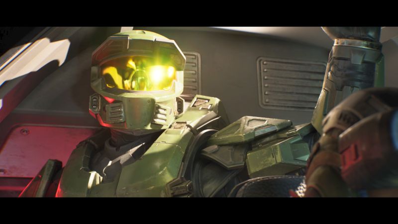El Master Chief en una cinemática de Halo: Campaign Evolved Primer plano del Master Chief sentado dentro de un vehículo de transporte, mostrando el reflejo dorado de su casco y el detalle de su armadura verde Spartan en una cinemática del juego.