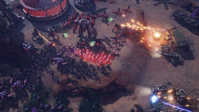 Enfrentamiento multitudinario que muestra a un mecha gigante rojo disparando misiles sobre una horda de criaturas alienígenas moradas que asaltan la base.