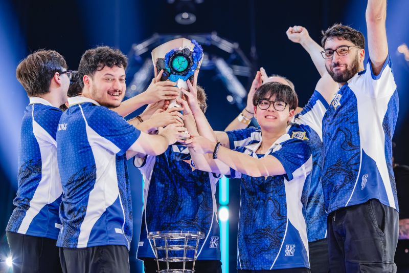 Equipo de esports celebrando un campeonato en un escenario iluminado, levantando un trofeo de diseño metálico y tonalidades azules.