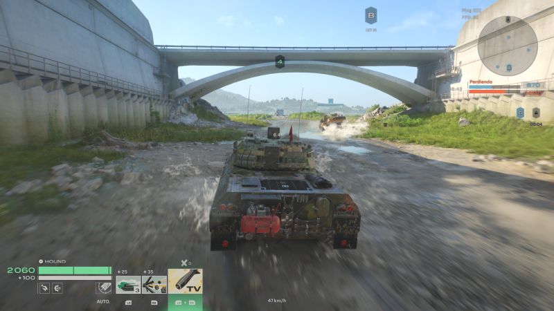 Tanque avanzando por un canal bajo una estructura de concreto.