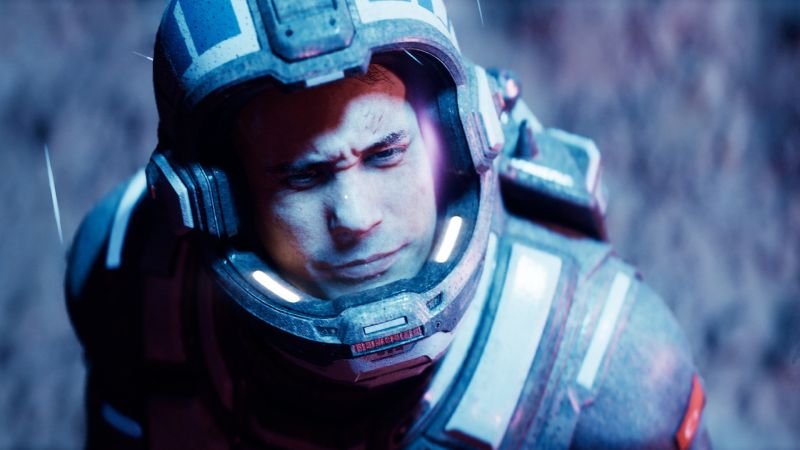 Primer plano de un astronauta con casco iluminado en un entorno rocoso y oscuro, con luces azuladas y púrpuras reflejadas en el visor.