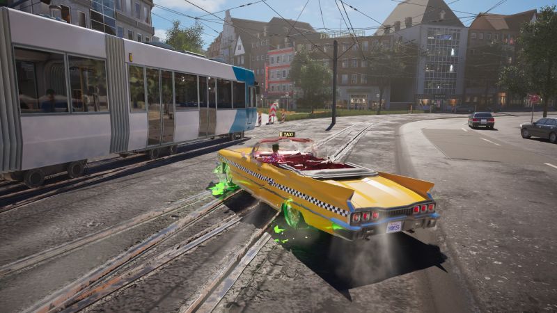 El taxi descapotable ejecutando un derrape con humo sobre las vías de un tranvía junto a un vagón en movimiento.