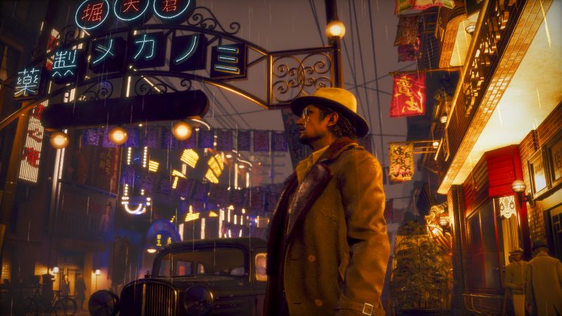 Makoto Daito con abrigo y sombrero caminando por una calle iluminada por letreros de neón junto a un automóvil clásico de época.