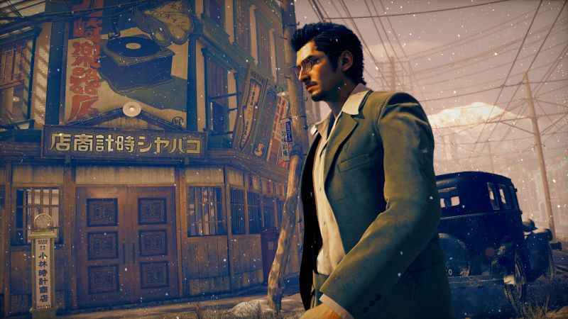 Makoto Daito de perfil luciendo traje elegante y lentes caminando por una acera mientras cae nieve en la ciudad.