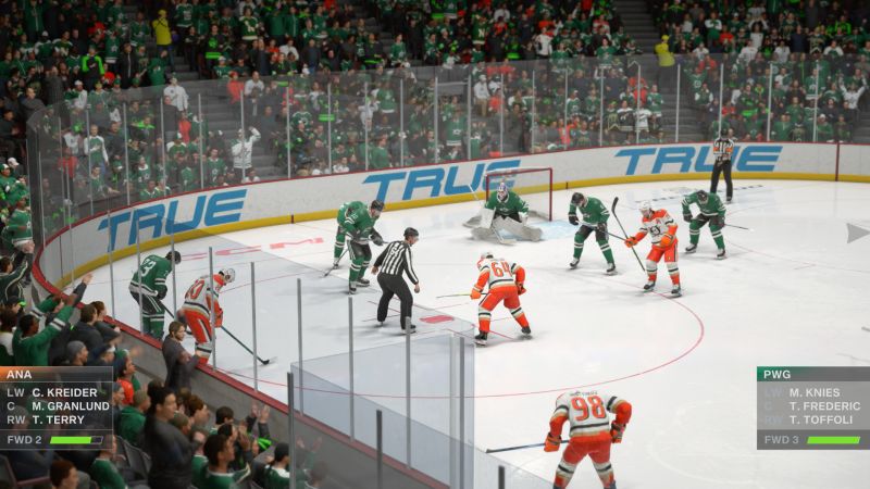Captura de pantalla de gameplay durante un saque neutral o faceoff cerca de la portería en una arena llena de aficionados vestidos de verde.